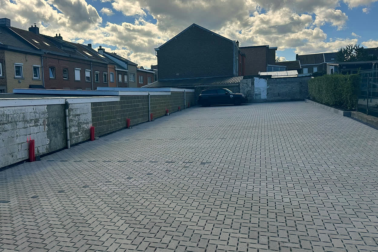 Le parking vu depuis son entrée, avec les maisons voisines en arrière-plan